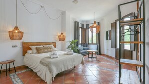 Une chambre à coucher avec un lit, des tables de chevet, un luminaire suspendu et une vue sur l’extérieur.