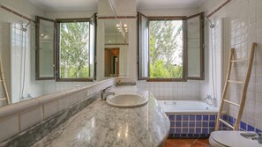 A bathroom with a marble sink, a bathtub, and a large mirror. - Casa Sensaciones Castaño del Robledo by Ruralidays (Huelva)