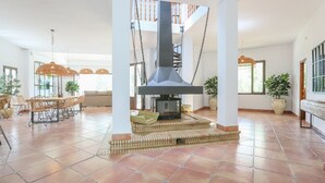 Un vaste espace de vie doté d’une cheminée, de sièges confortables et de grandes fenêtres.