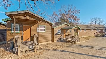 A row of wooden cabins with a gravel driveway and a clear sky.