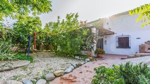 A courtyard with a swing set, a white building with a tiled roof, and a stone pathway. - Cortijo Relatillos Albox by Ruralidays (Almería)