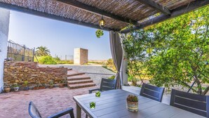 An outdoor patio with a table and chairs, a stone wall, and a view of a building in the distance. - Cortijo Relatillos Albox by Ruralidays (Almería)