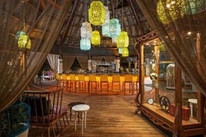 An interior with a bar area, wooden flooring, and hanging lanterns.