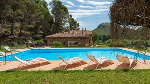 A swimming pool with lounge chairs, a stone building, and a mountainous backdrop. - Valdemarín Rural Cortijos Nuevos by Ruralidays (Jaén)
