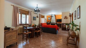 A cozy living room with a fireplace, a dining area with wooden furniture, and a kitchen area with a stove and cabinets.