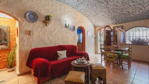 Un interior acogedor con un sofá rojo, una mesa de comedor con sillas y una pared decorativa con platos.