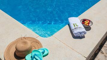 A poolside setting with a towel, hat, and flip-flops.