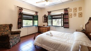 A hotel room with a bed, a chair, a dresser, and a window with curtains.