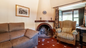 A living room with a brown sofa, a striped armchair, a fireplace, and a framed picture on the wall.