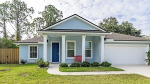 Une maison de plain-pied avec un porche à l’avant, un garage et une pelouse bien entretenue.