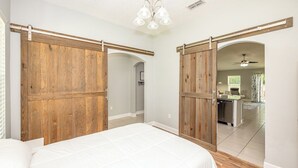 Une chambre avec un grand lit, des portes coulissantes en bois et une vue sur une autre pièce.
