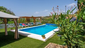 A swimming pool with a pergola and lounge chairs, surrounded by well-maintained grass and plants. - La Casa del Sauce Archidona by Ruralidays (Málaga)