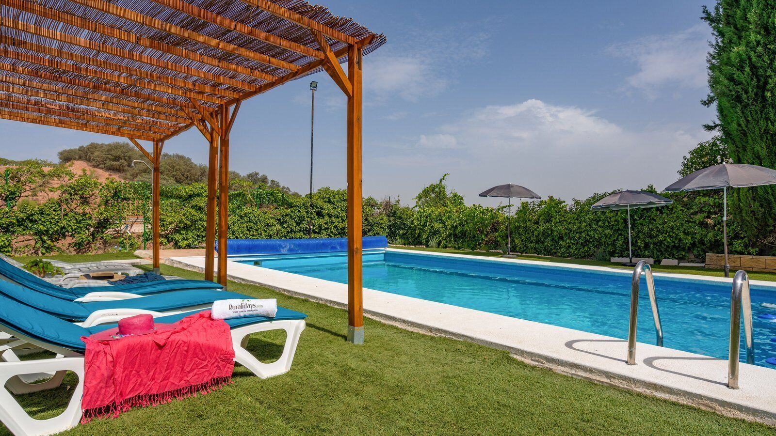 Area piscina con lettini, una pergola e cielo azzurro.
