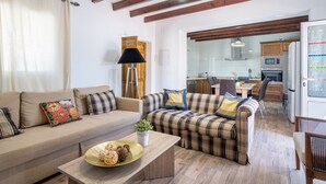 Un salon comprenant un ensemble de canapés, une table basse agrémentée d’objets décoratifs et donnant sur la cuisine.