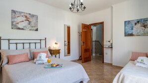 Quarto de hotel com duas camas, um lustre, obras de arte nas paredes e um tabuleiro de café da manhã sobre uma das camas.