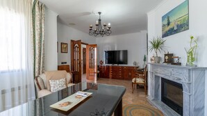 Uma sala de estar com televisão, lareira e um espaço de jantar com mesa e cadeiras.