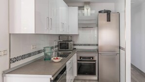 Una cocina moderna con armarios blancos, un refrigerador de acero inoxidable, un microondas y un horno.