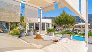 Un balcón con cama, plantas en macetas y vista a la piscina.
