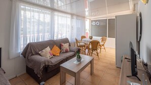 A living room with a sofa, coffee table, and dining area with chairs and a table. - Villa Mariposas Torrox by Ruralidays (Málaga)