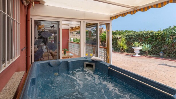 A hot tub area with a glass door leading to a patio with plants and a view of the city. - Villa Mariposas Torrox by Ruralidays (Málaga)