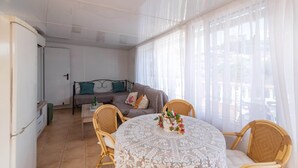 A cozy living room with a sofa, a dining table with chairs, and a view through sheer curtains. - Villa Mariposas Torrox by Ruralidays (Málaga)