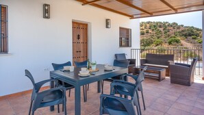Eine Terrasse mit Tisch und Stühlen, eine Tür und Blick auf eine hügelige Landschaft.