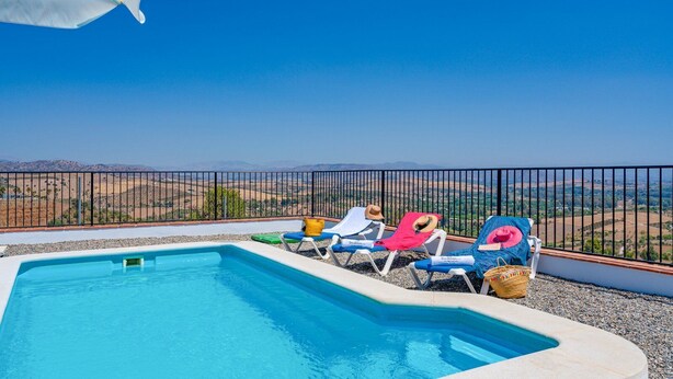 Ein Swimmingpool mit Liegestühlen und Blick auf eine hügelige Landschaft.