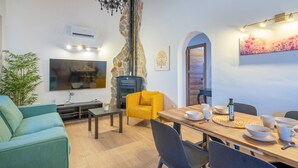 Ein modernes Wohnzimmer mit Fernseher, Sofa, Esstisch und Kamin.