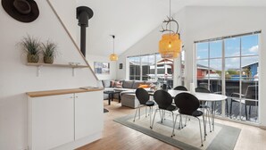 Una cocina moderna con armarios blancos, encimera de madera y un colgador para ollas.