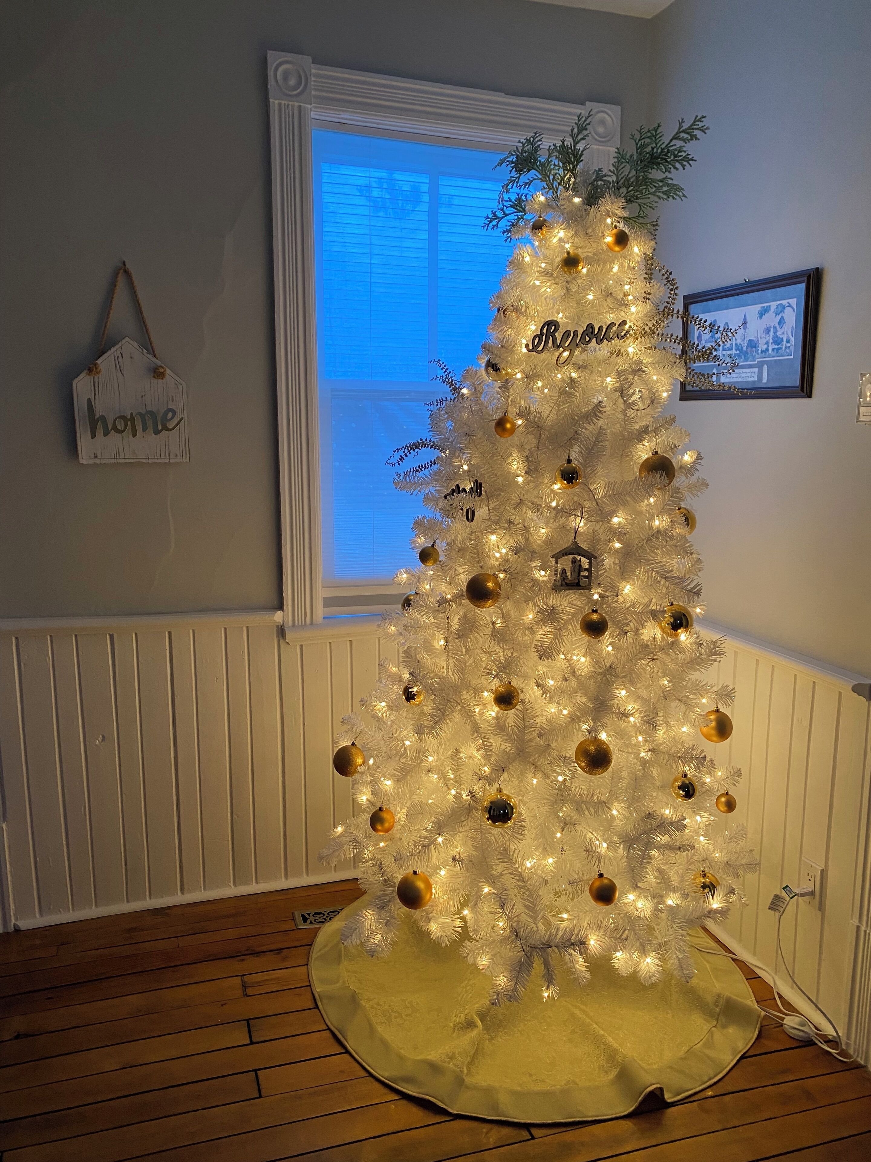 A white Christmas tree with gold ornaments, a 'Home' sign, and a 'Roses' sign on the wall.