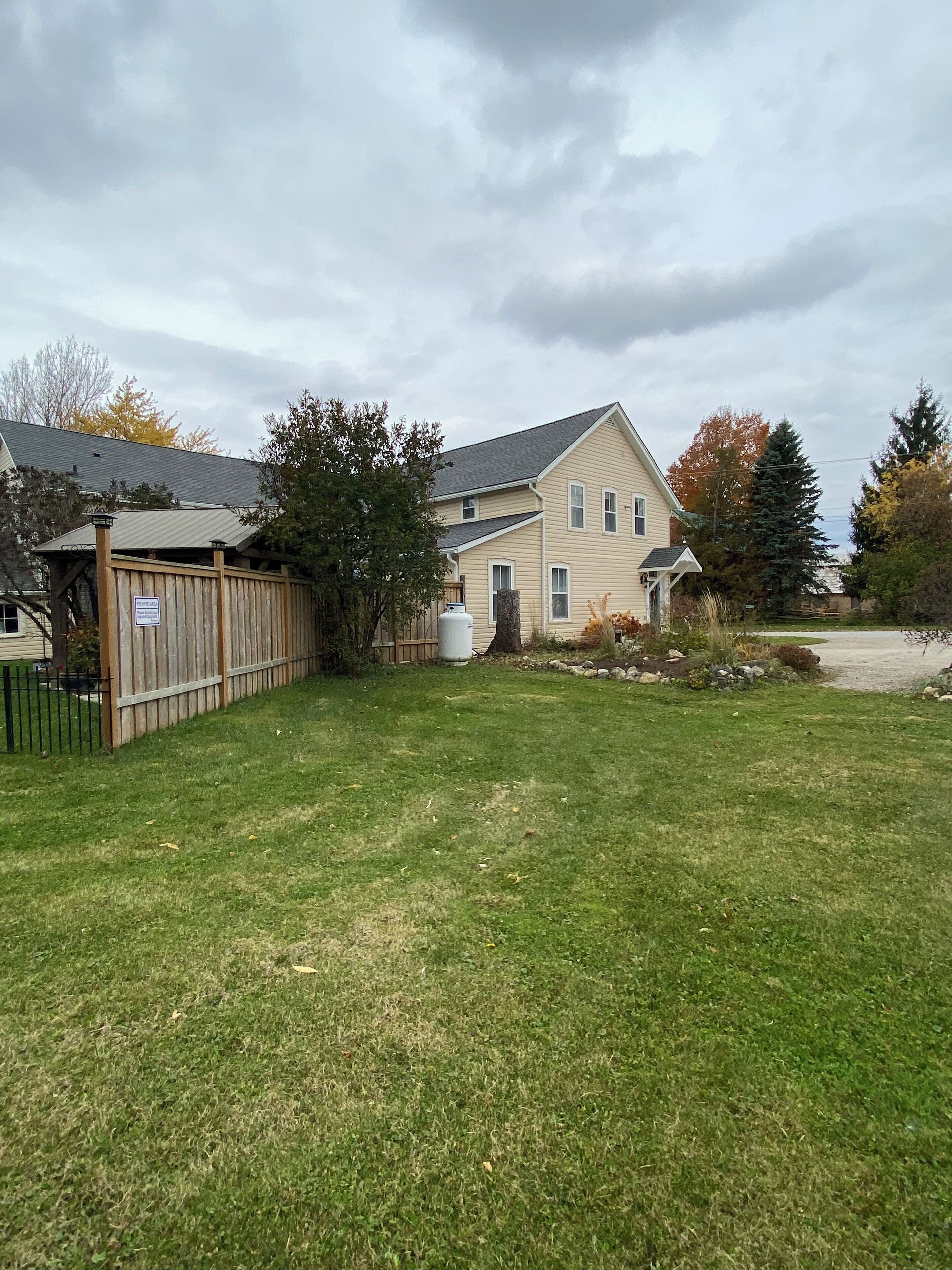 A two-story house with a fenced backyard, a water tank, and a sign indicating a private road.