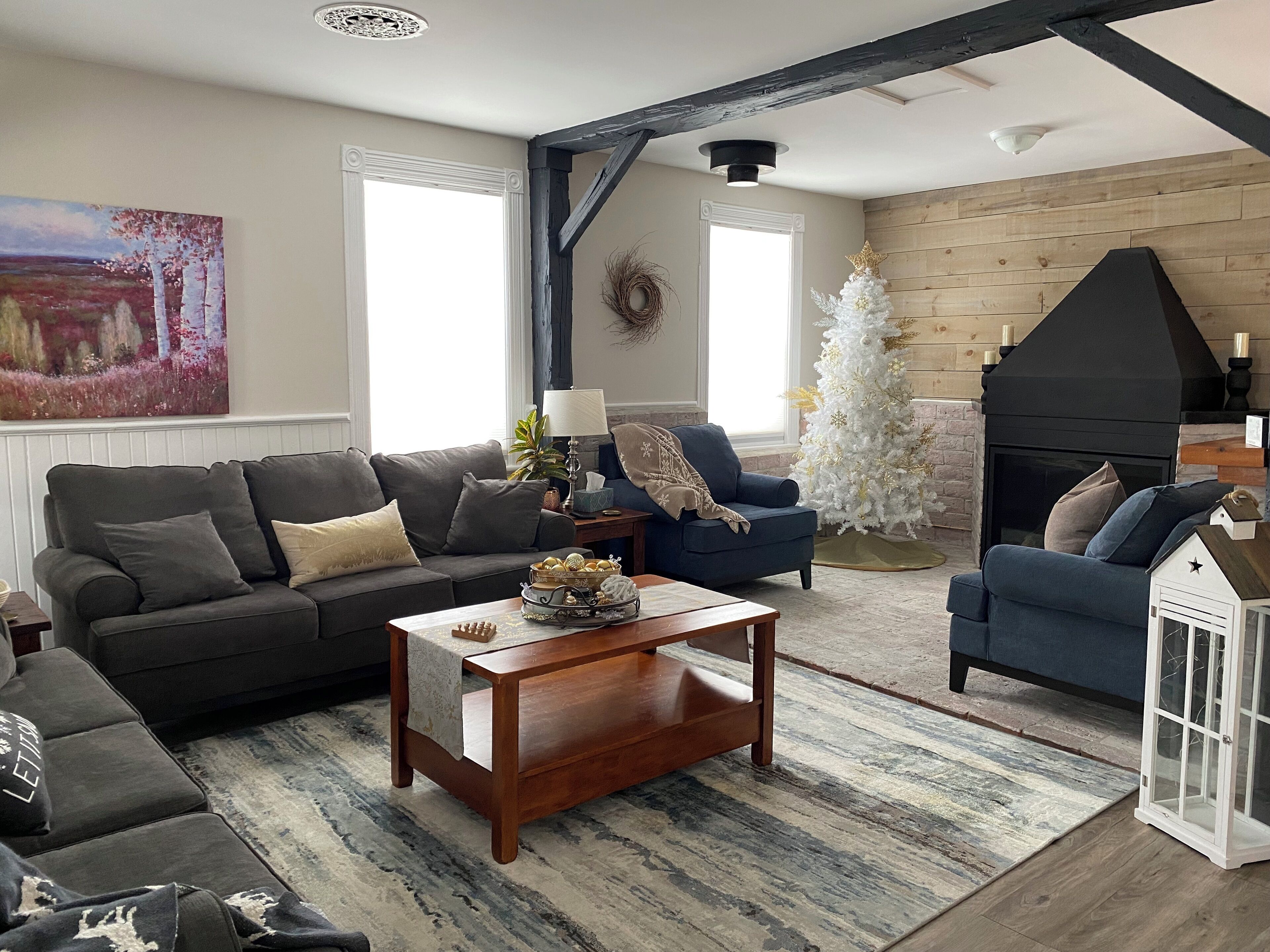 Una sala acogedora con chimenea, un árbol de Navidad blanco y un cuadro grande en la pared.