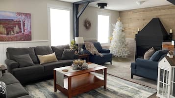 Una sala acogedora con chimenea, un árbol de Navidad blanco y un cuadro grande en la pared.