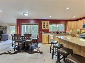 A modern kitchen with wooden cabinets, a large island, and a dining area with chairs.