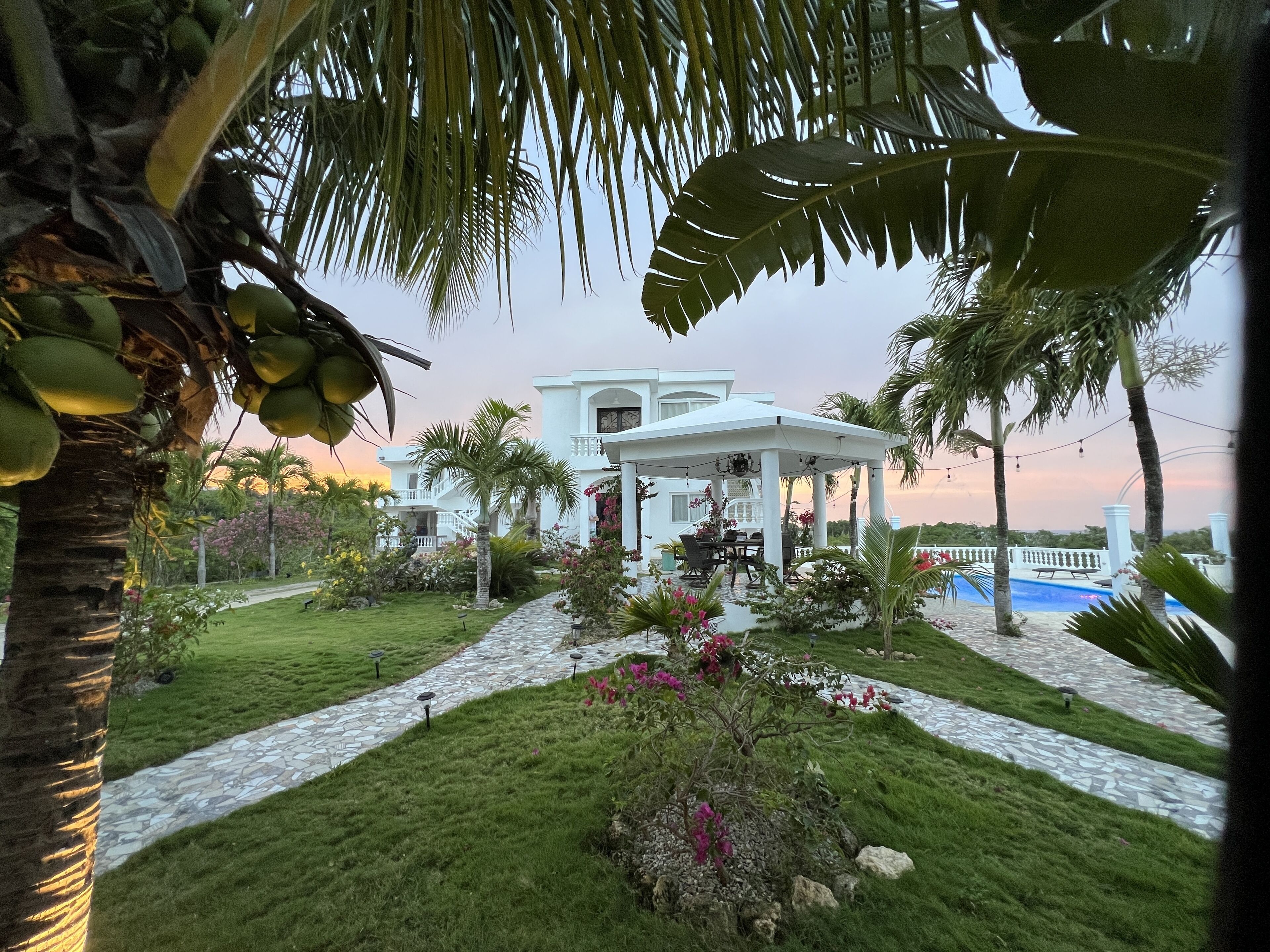 A white building with a covered patio and a pool.