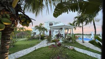 A white building with a covered patio and a pool.