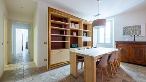A dining area with a wooden table and chairs, a bookshelf, and a pendant light. - Boutique Apartment Near Spanish Steps (Roma)