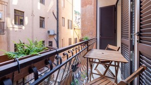 A narrow balcony with a wooden table and chairs, a metal railing, and a view of adjacent buildings. - Boutique Apartment Near Spanish Steps (Roma)