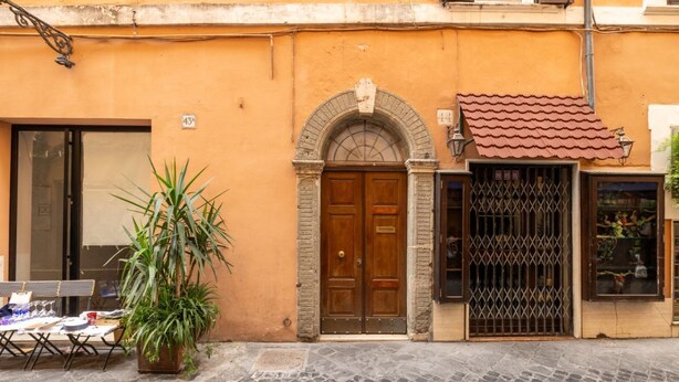 A street view with a building featuring a wooden door, a metal gate, and a potted plant. - Boutique Apartment Near Spanish Steps (Roma)