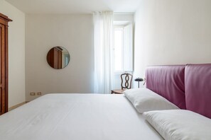 A bedroom with a large bed, a round mirror, a wooden wardrobe, a chair, and a window with curtains. - Boutique Apartment Near Spanish Steps (Roma)