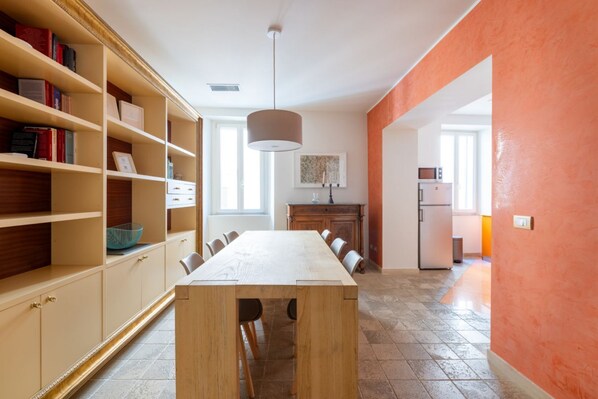A modern kitchen with a wooden table and chairs, a built-in bookshelf, and a pendant light. - Boutique Apartment Near Spanish Steps (Roma)