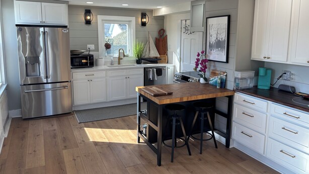 Una cocina moderna con armarios blancos, electrodomésticos de acero inoxidable y una isla de madera.