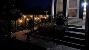 Una casa con porche, escalones y jardín iluminado.