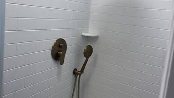 A shower area with white tiled walls and a showerhead.