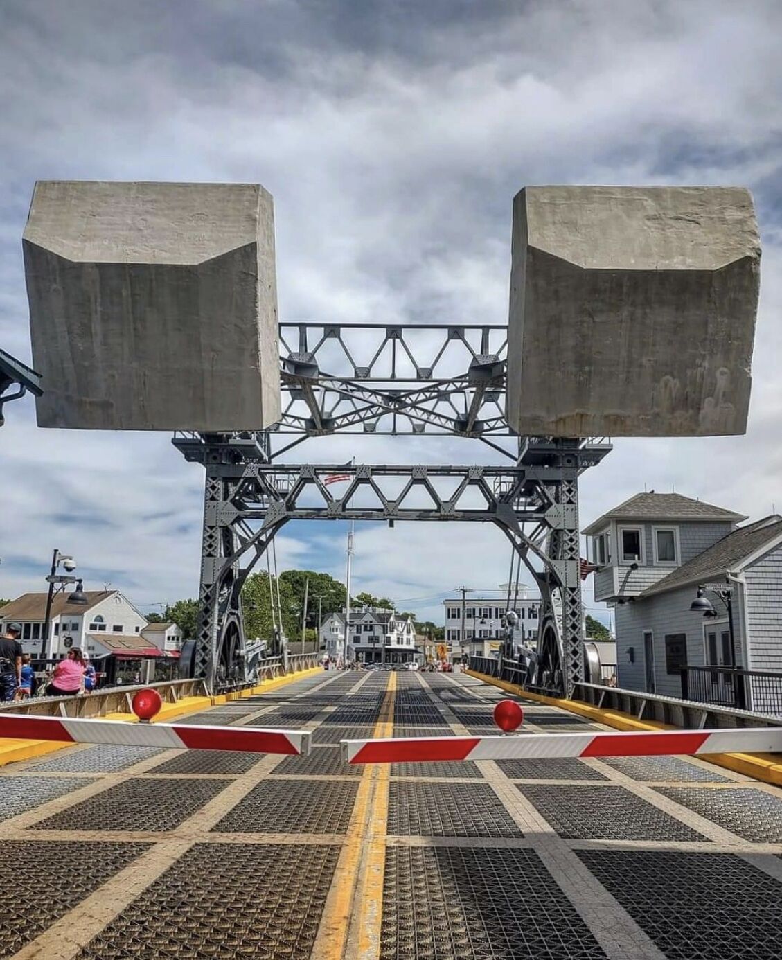 Un puente peatonal con estructura de celosía metálica y soportes de hormigón.