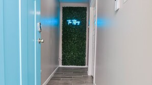 Ein Flur mit einer blauen Tür, einem Neon-Schild mit der Aufschrift "The Tiffany" und einer blauen Fußmatte, die ebenfalls diesen Namen trägt.