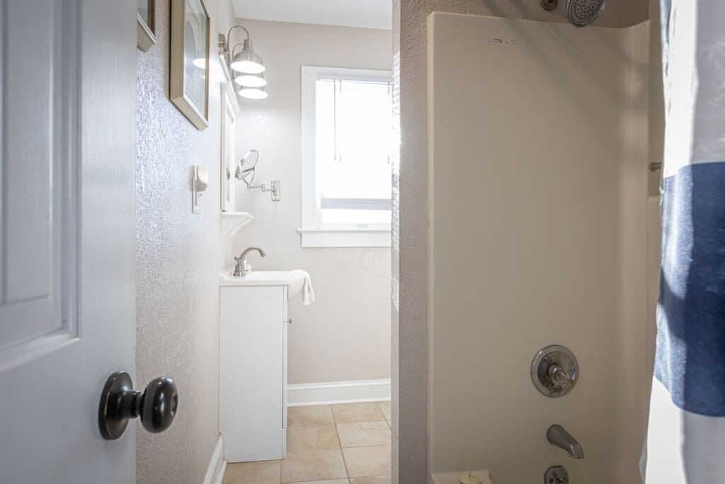 A bathroom with a sink, mirror, and shower.