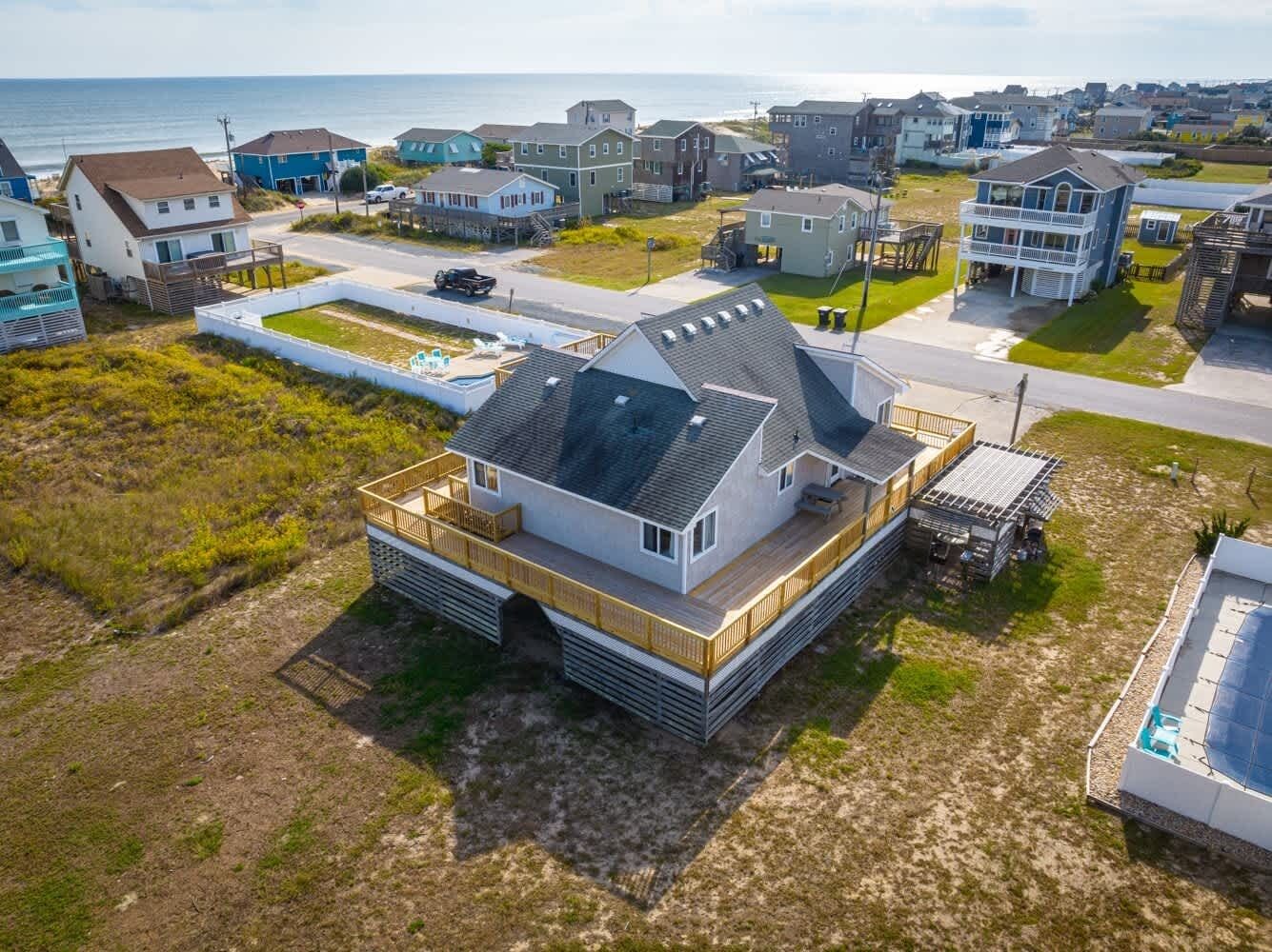 A coastal house with a large deck, a covered outdoor area, and a view of the ocean.