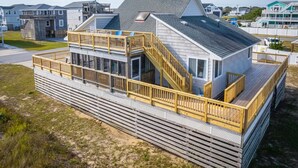 A modern coastal house with a deck, a staircase, and a large window. - New 2026 Renovations Retreat Just Steps to Beach! (Kitty Hawk)