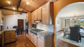 A kitchen with wooden cabinets, a stove, and a dining area with a table and chairs.